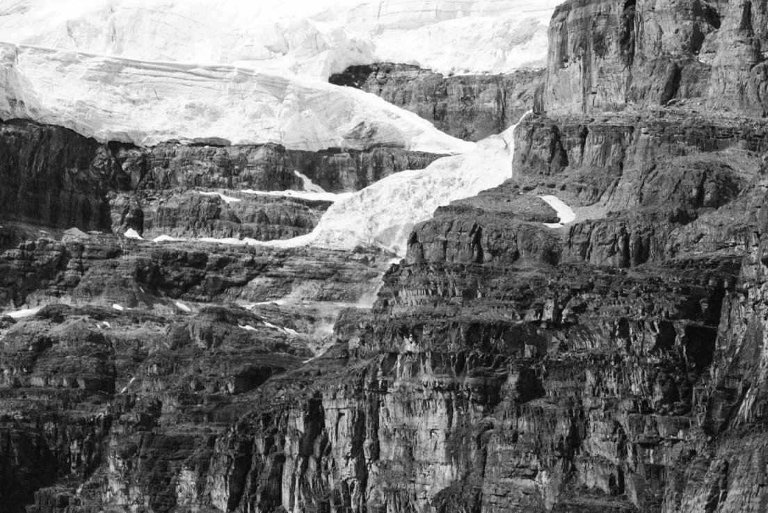 Black and white photograph of layers of snow on a cliff on the Three Glaciers Trail