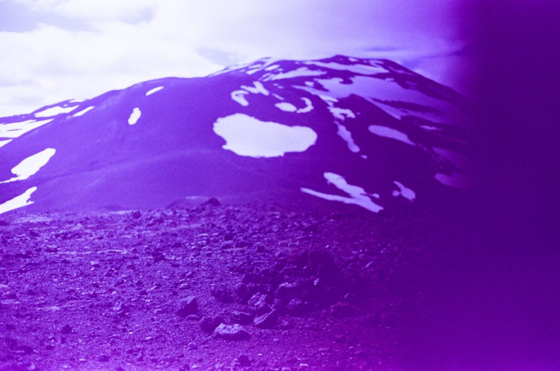 Purple-tinted photograph of the summit of the volcano with patches of snow, Hekla volcano
