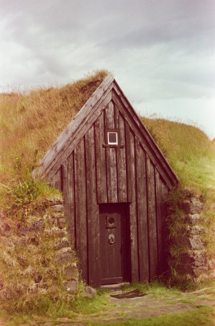 Slightly magenta-tinted photograph of a traditional icelandic farmhouse with moss-covered rooftop, Keldur