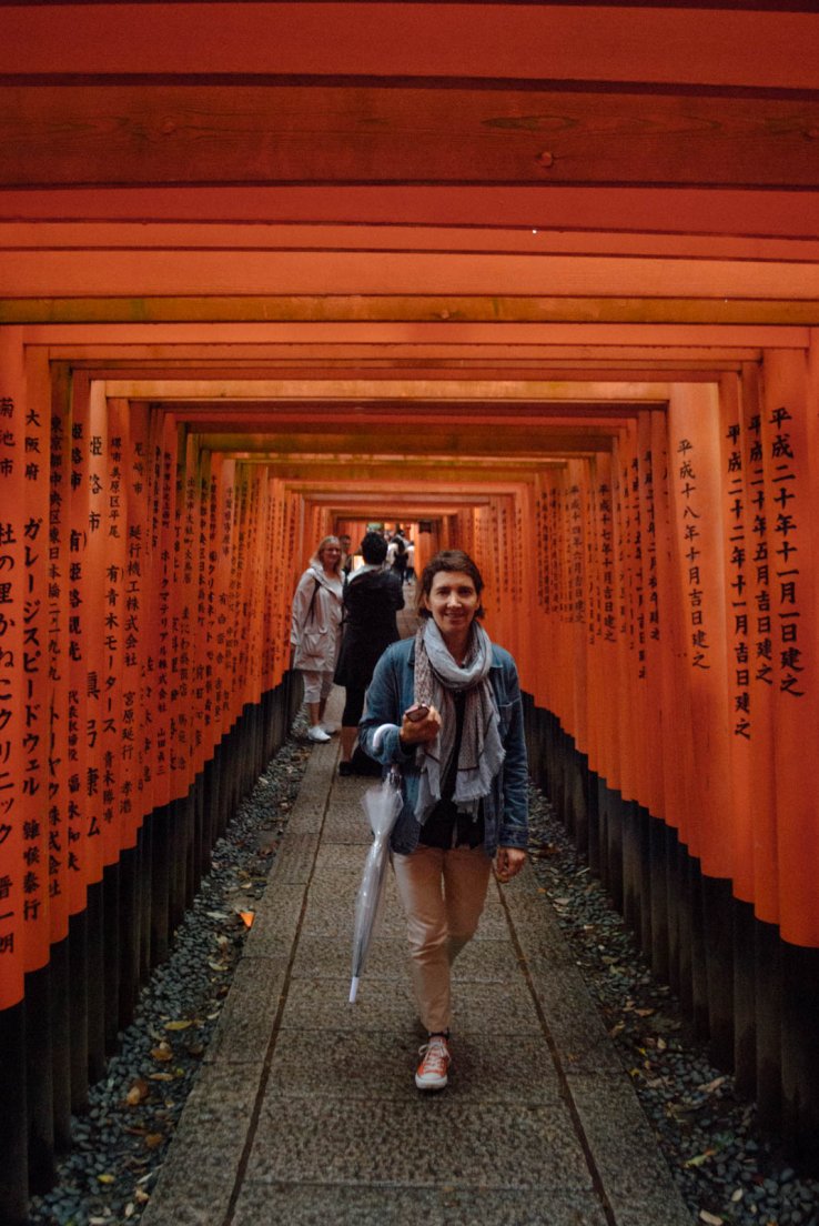A tourist lady in an alley of torii