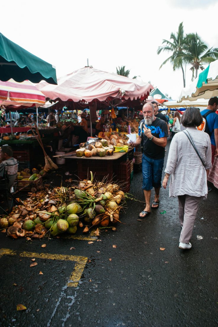 Tourists and locals passing by the coconut stall at a food market