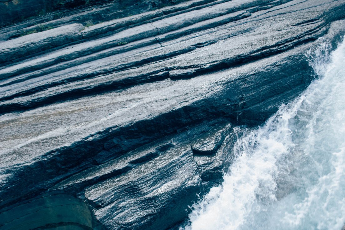 Parallel rock textures and rushing water at the Mistaya Canyon