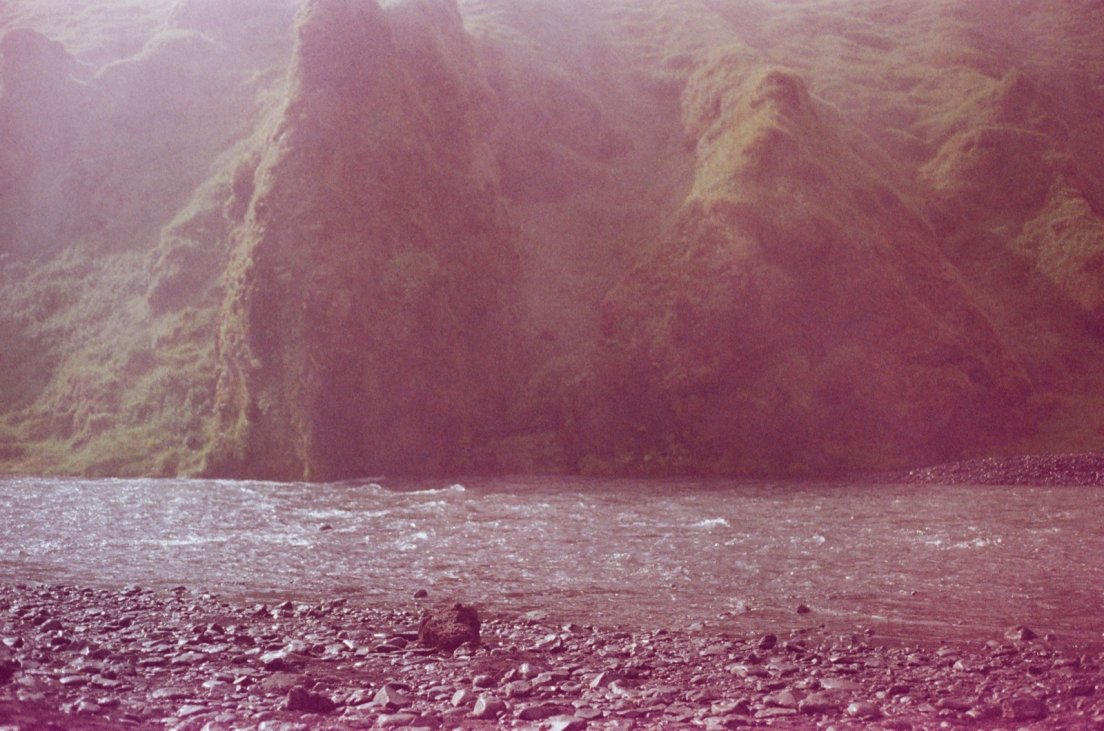 Magenta-tinted photograph of the river coming out from the waterfall