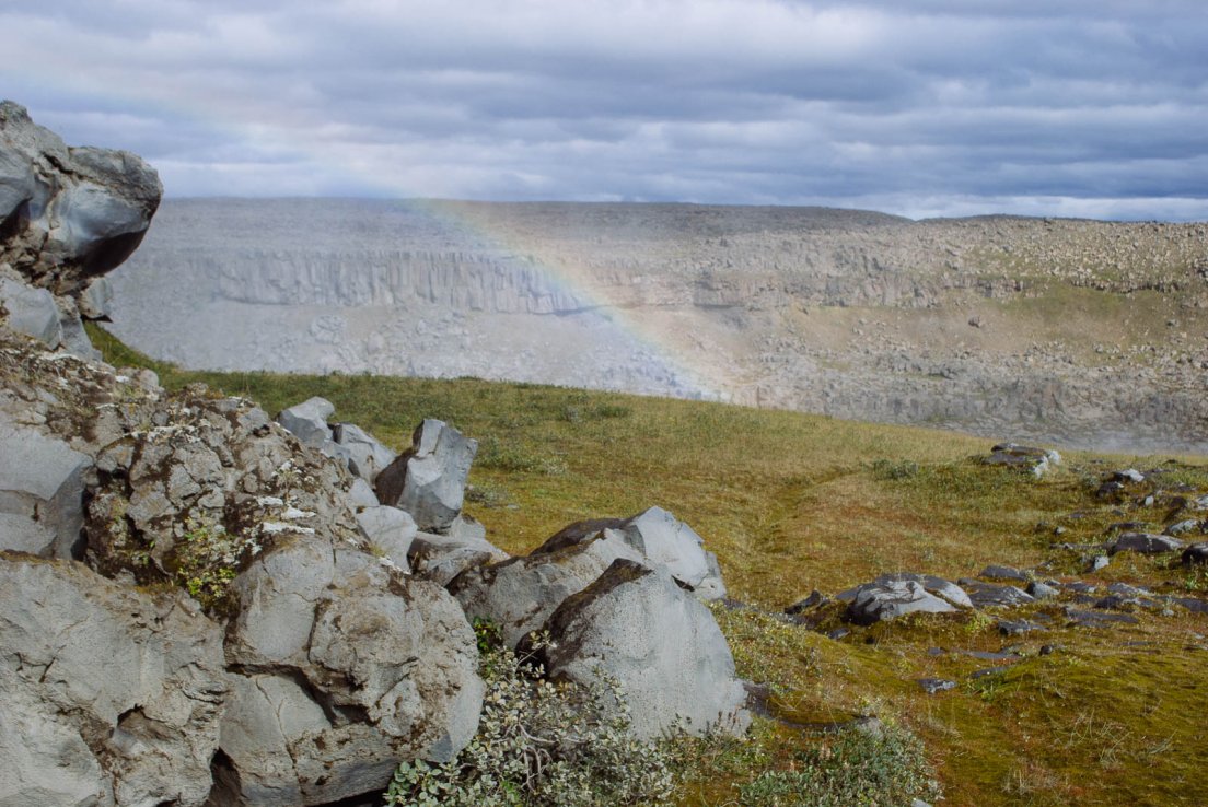 A rainbow occurring above an unseen waterfall on a cloudy da