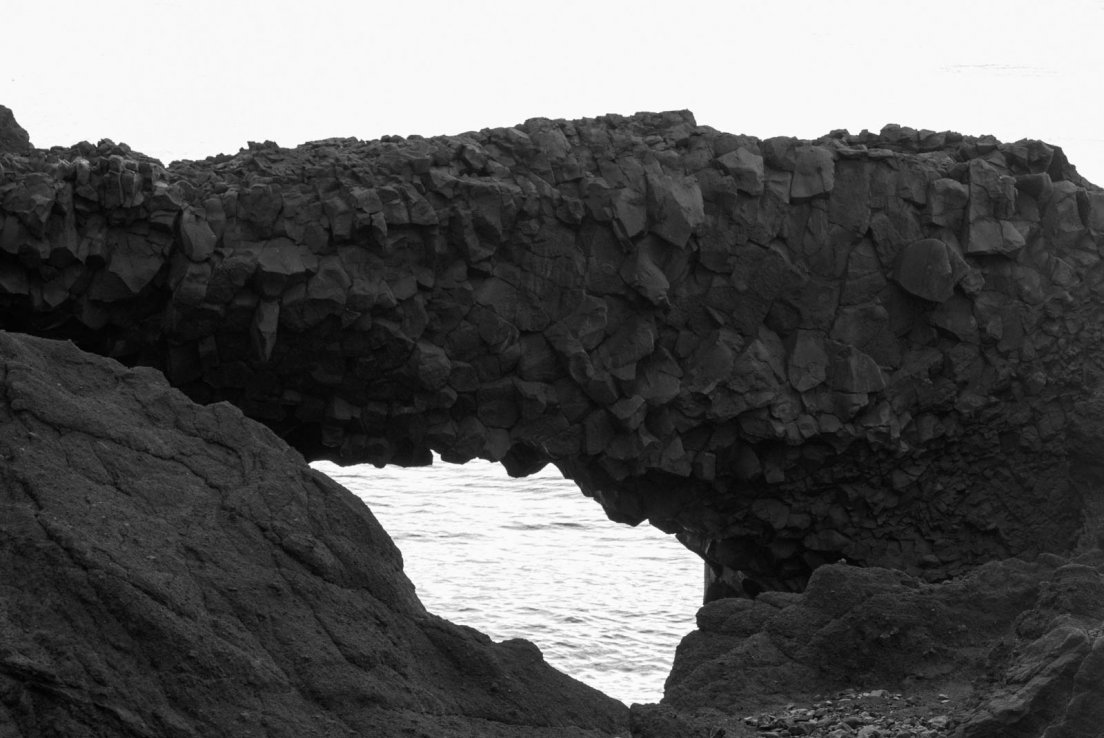 Black and white photograph of a lava arch