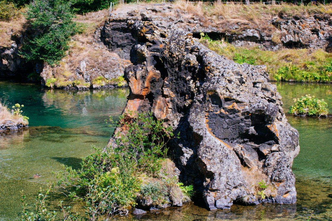 Large volcanic rock in the middle of the lake on a sunny summer day