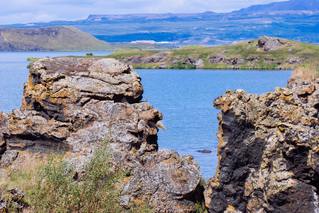 Large volcanic rocks facing a lake on a sunny summer day
