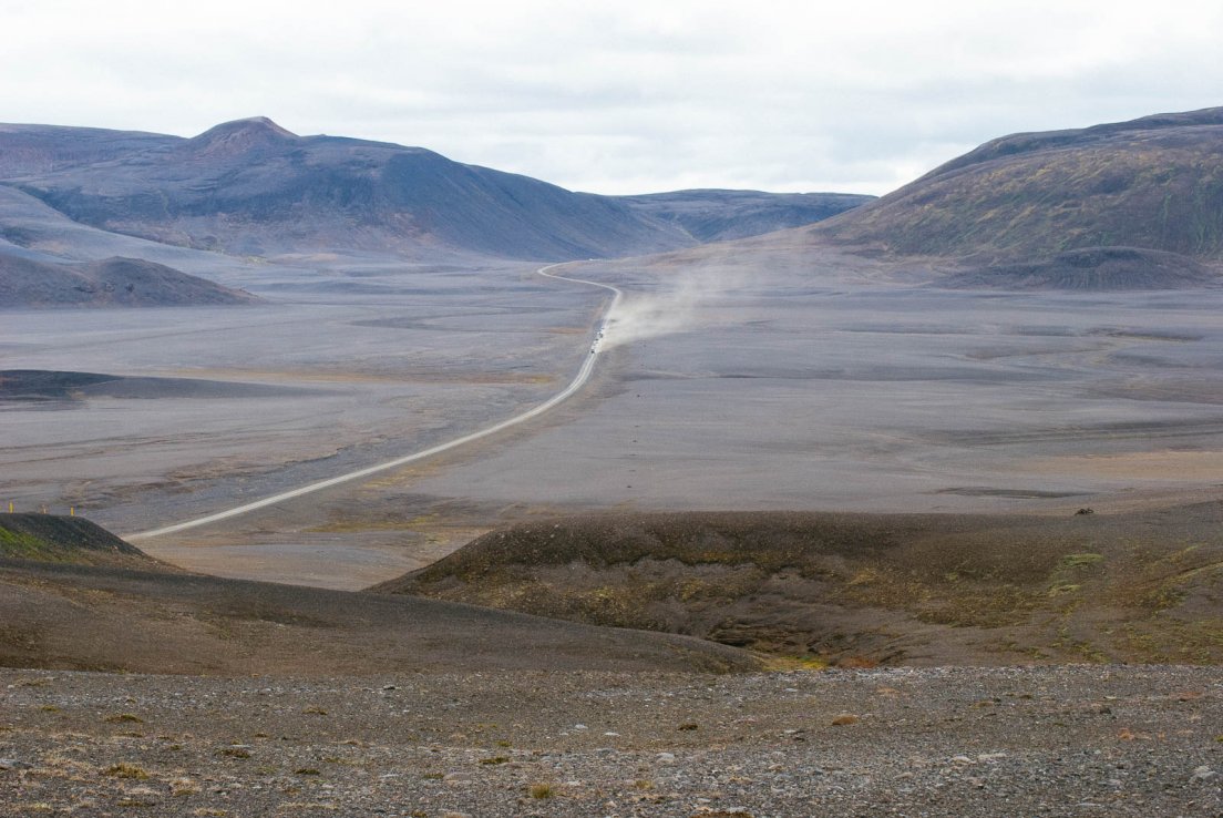 Cars driving on a dusty road in the middle of nowhere