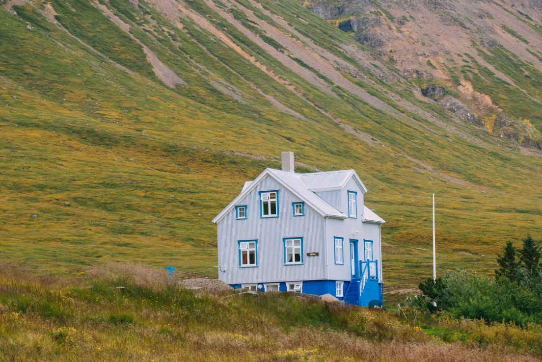 Typical icelandic house in white x blue corrugated metal in the middle of a valley
