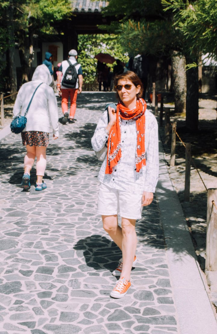 A western lady with a light blue shirt and red scarf is standing in front of the entrance to the temple