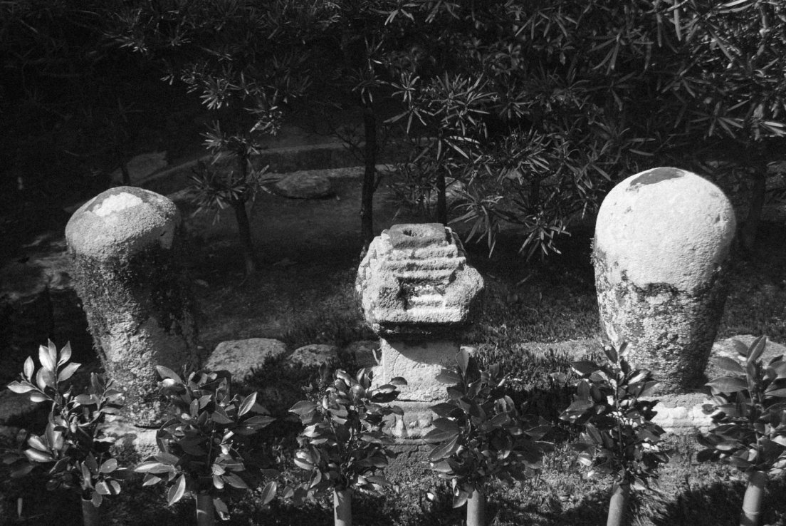 Black and white photograph of three short stone pillars in the gardens