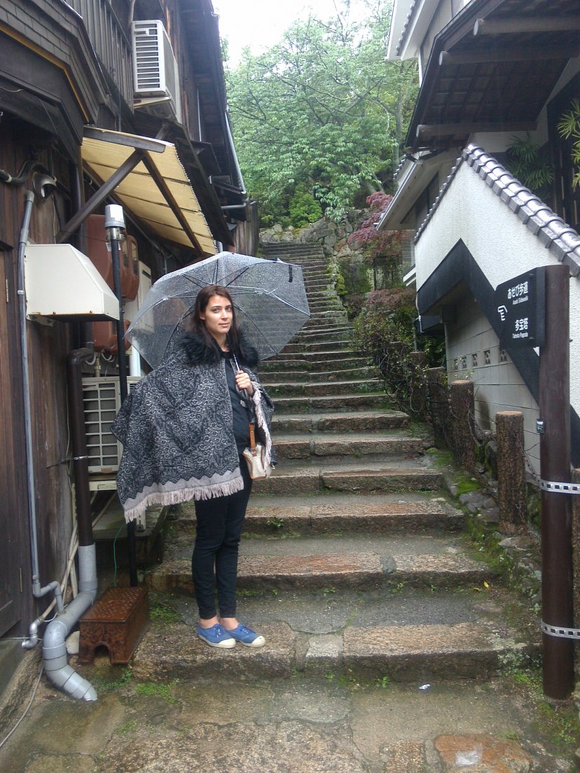 Girl with a poncho and a transparent umbrella standing on the stairs of a narrow street, Miyajima, 10 may 2016 Girl with a poncho and a transparent umbrella standing on the stairs of a narrow street