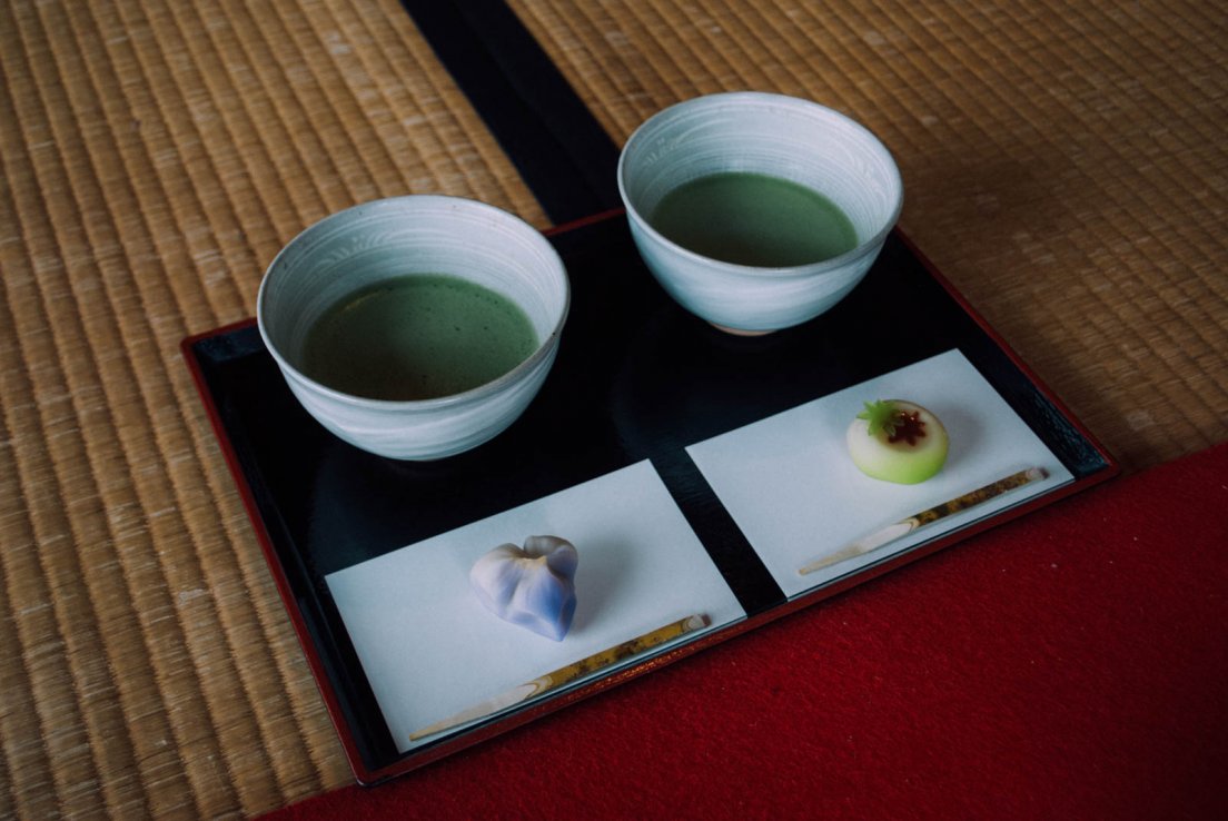 A serving of traditional japanese tea with matcha and seasonal side pastries, shaped as an iris and a green maple leaf