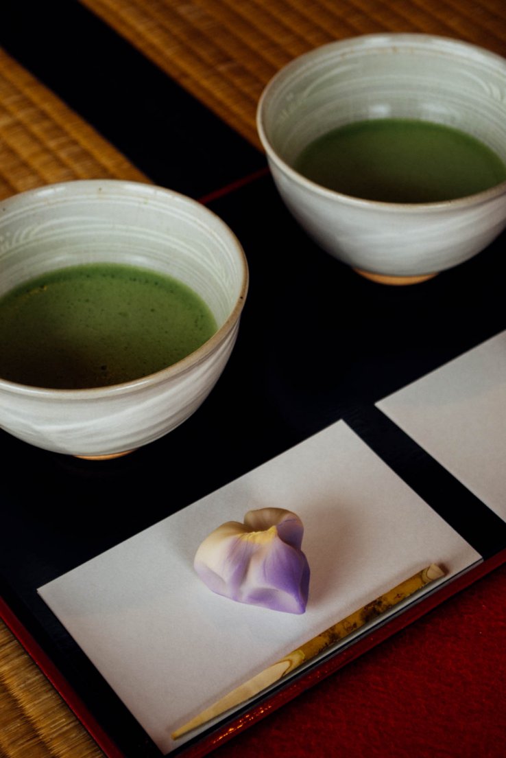 A serving of traditional japanese tea with matcha and a seasonal side pastry shaped as an iris
