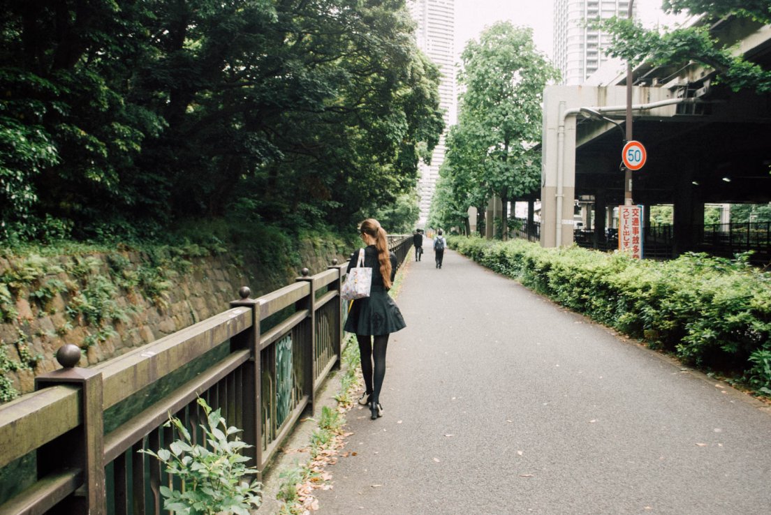 A girl walking away near a canal in an urban area