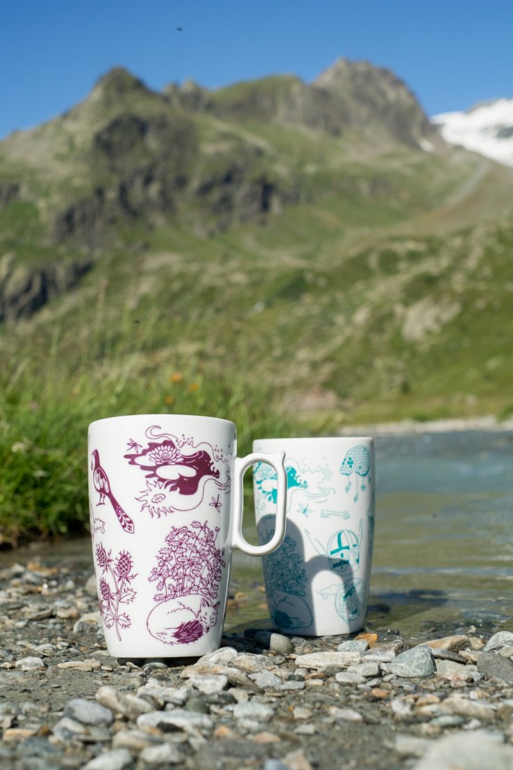 Purple and seafoam mugs from Enchanteresse, a hand-painted porcelain collection by messalyn, on the shoreline of a mountain torrent